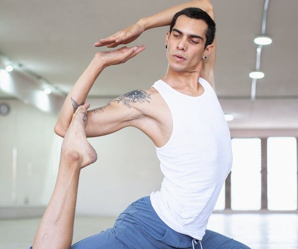 A focused man in athletic wear stretching indoors with natural light.