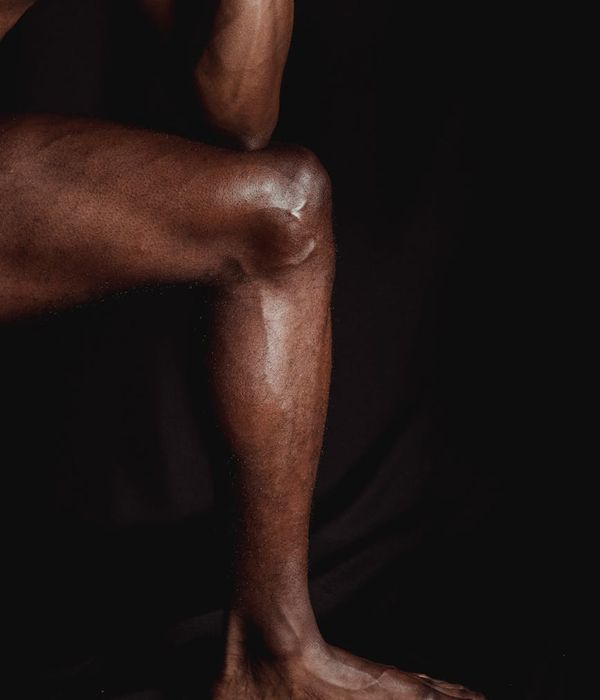 Man performing a controlled strength exercise in a dark, minimalist gym.